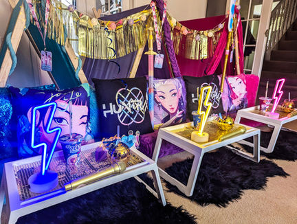 Colourful room with themed Huntrix pillows and neon lights.