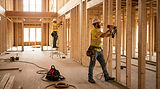 carpenters working framing walls in the interior of a large residential building