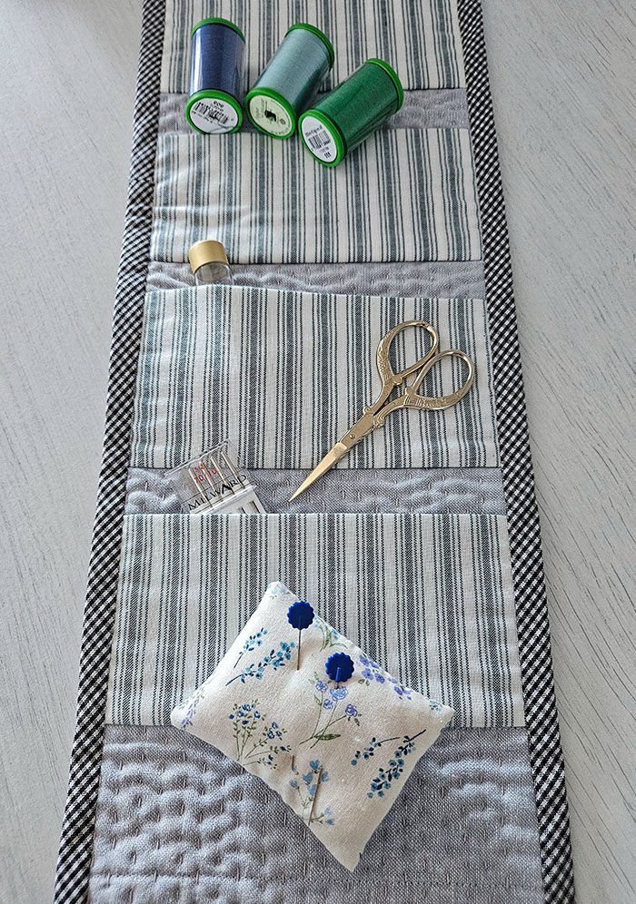 Thumbnail: flat view of the inside of a cotton fabric sewing roll filled with sewing accessories in multi colours