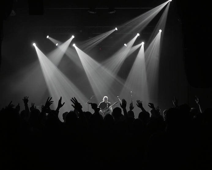 Grey silhouetted cheering concert crowd in dark room with laser lights silhouetting a band
