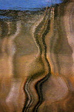 A harbour side ladder's reflection contorts and twists in calm waters at Porthgain in Pembrokeshire.