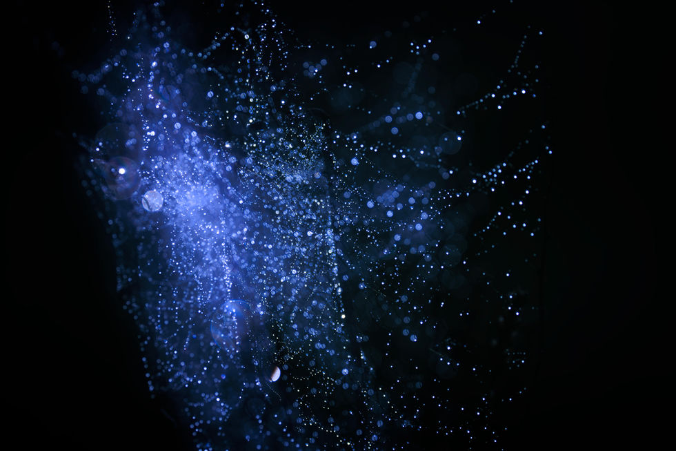 An abstract fine art study of light and moisture: shimmering blue bokeh and glittering dew-covered silk threads of a spider web, creating a cosmic, nebula-like effect.