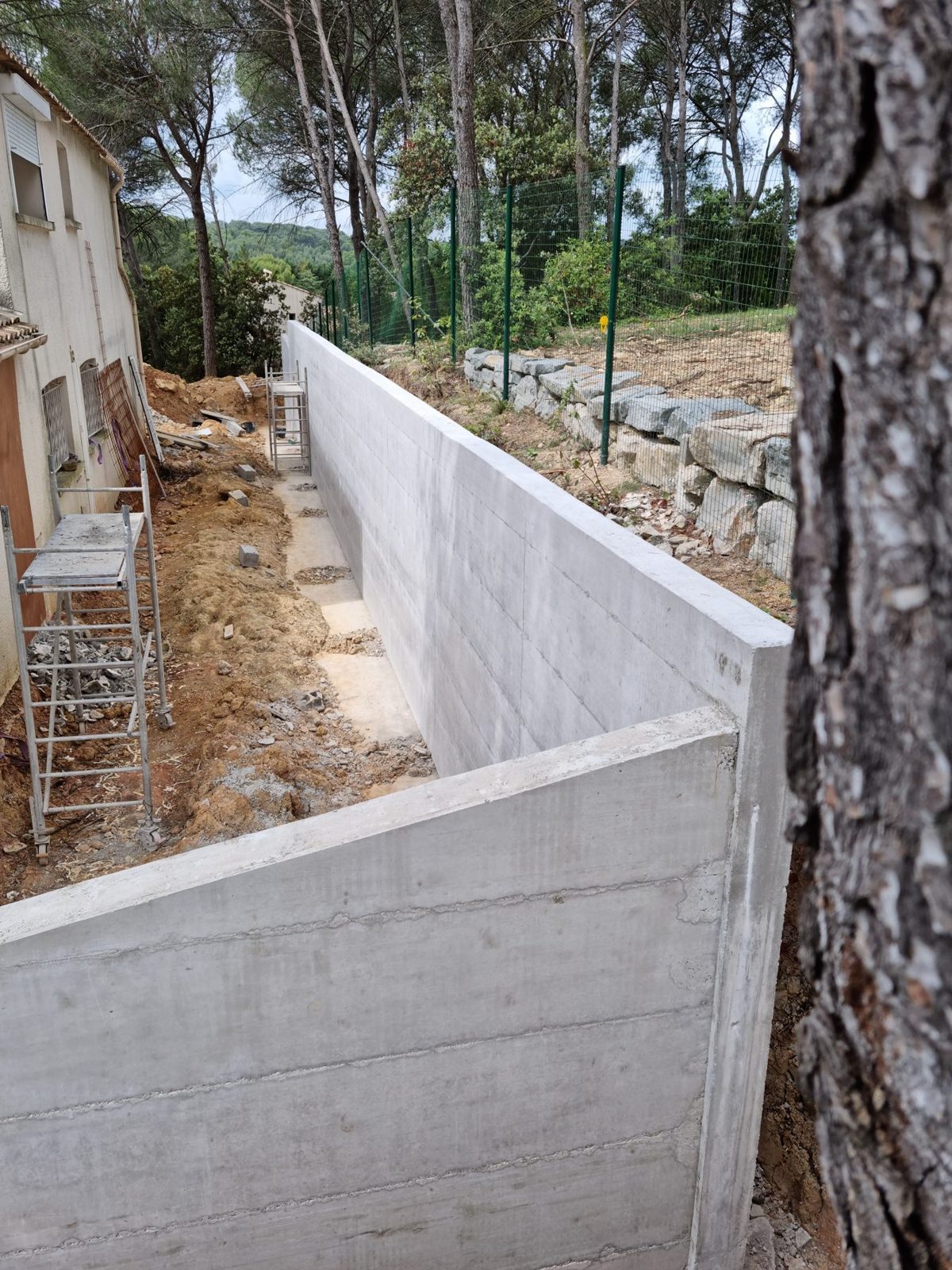 Mur de soutènement en béton banché le long d'une maison