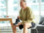 A man sitting at kitchen table putting a custom foot orthotic into a pair of running shoes