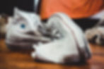 A pair of old beat up dirty converse high top sneakers on a wooden floor