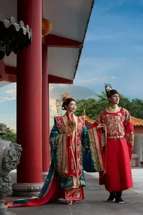 The couple walk together during their pre wedding photoshoot, showcasing detailed embroidery on their outfits.