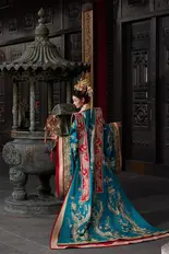The bride stands beside a stone lantern, wearing an ornate blue gown during a pre wedding photoshoot.