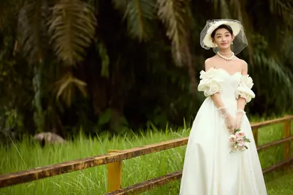 Bride wearing an off-shoulder white gown and wide-brimmed hat.
