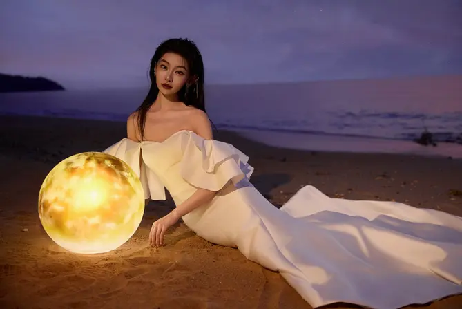 Bride in a white dress, poses on the beach with a seascape view for a pre wedding photoshoot.
