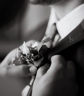 Groom adjusting boutonnière before wedding, representing Luxe Wedding Studio's attention to detail and tailored planning