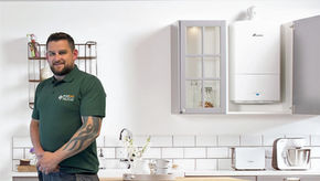 Smart Heat Experts engineer beside a wall-mounted boiler in a kitchen