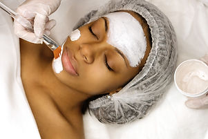 Application of cosmetology mask on the face of a young afro american woman. Procedure for 