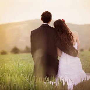Couple embracing in field, wedding attire