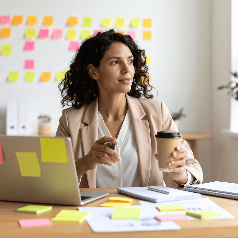 Thoughtful woman at desk holding coffee surrounded by sticky notes
