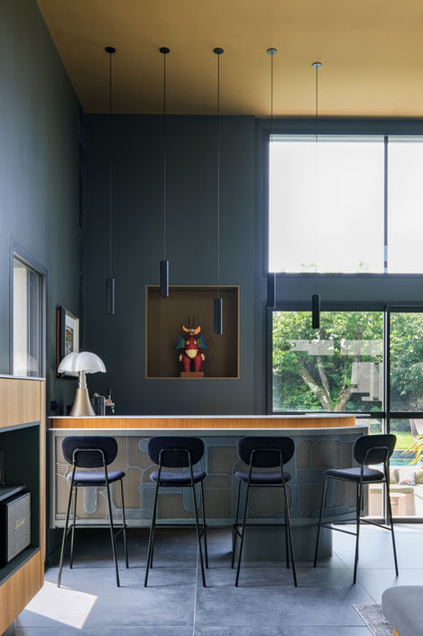 Salon contemporain de luxe avec verrière, mobilier design, plafond haut et éclairage suspendu, dans une villa moderne conçue par un architecte à Lyon, France, escalier métal devant patio bar sur-mesure