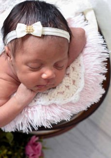 Bebê recém-nascida dormindo de bruços, vista de cima, envolvida em wrap em ensaio newborn na residência.