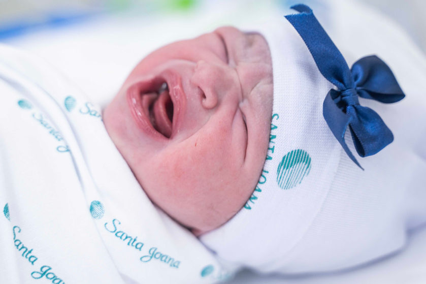 bebê chorando com a roupa da Santa Joana