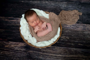 Recém-nascido no cesto de madeira, visto de cima, ensaio newborn em casa