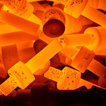 Primer plano de piezas metálicas incandescentes acumuladas en un horno industrial durante un proceso de tratamiento térmico.