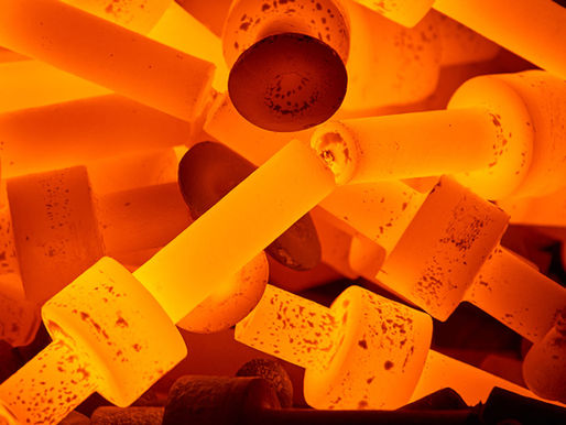 Primer plano de piezas metálicas incandescentes acumuladas en un horno industrial durante un proceso de tratamiento térmico.