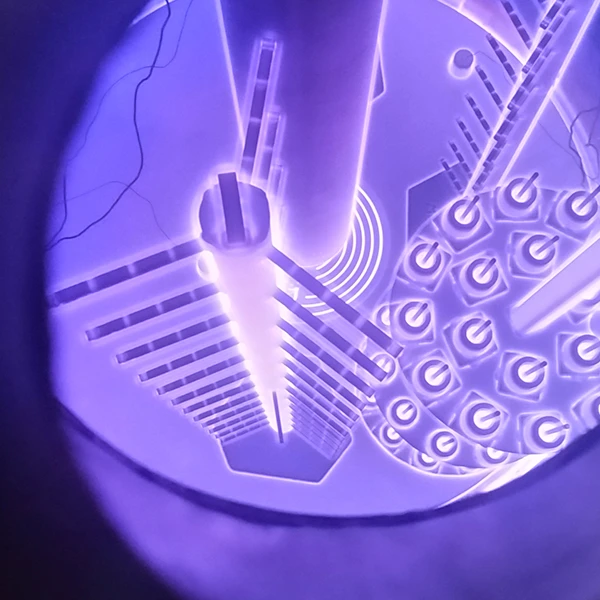 Interior de una cámara de nitruración por plasma que muestra componentes industriales envueltos en una aura de luz ionizada morada.