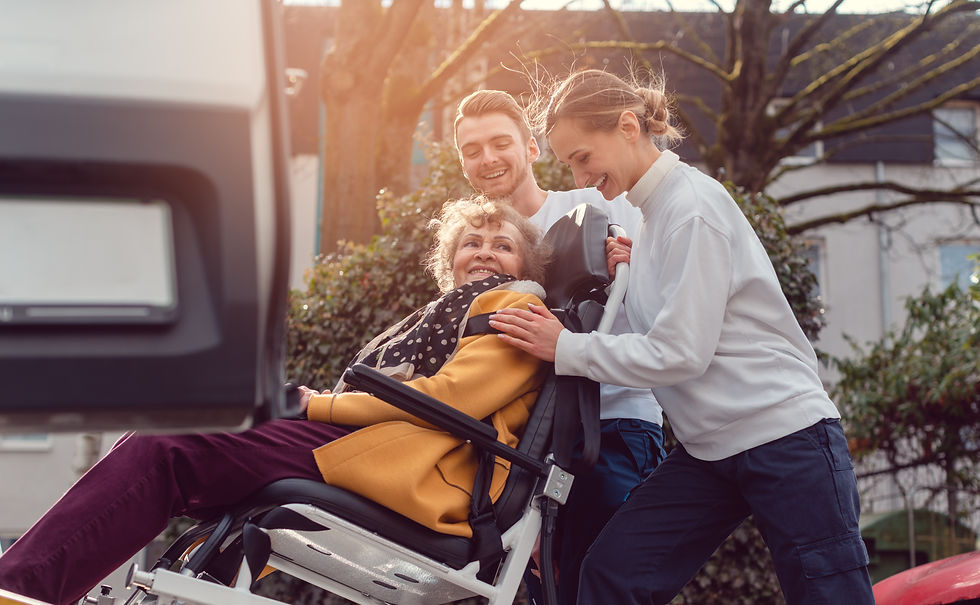 Two helpers picking up disabled senior woman in wheelchair for transport.jpg