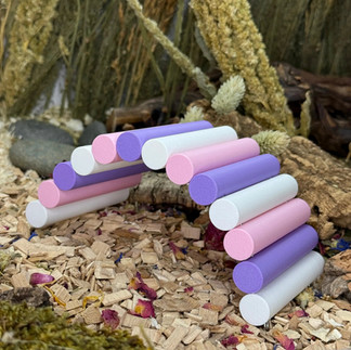 A 3D printed hamster bridge in white, purple and pink surrounded by beech chips and sprays in the background