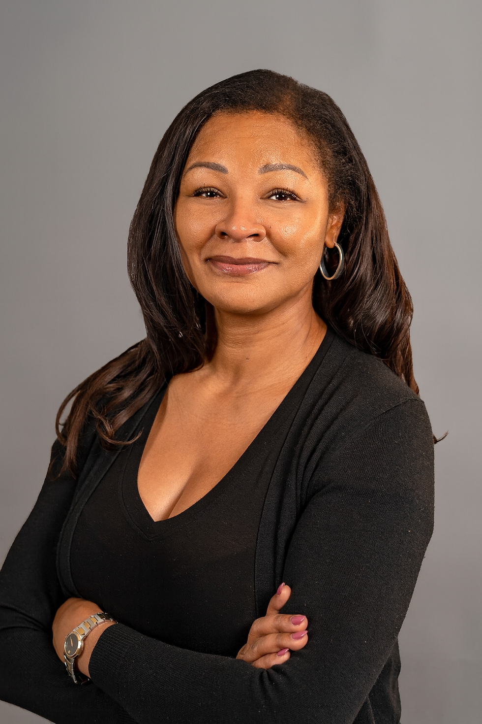 Portrait headshot of the founder against a neutral gray background, landscape crop focusing on face and upper torso, warm tones, black top.