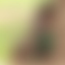 Three Ugandan children in tattered clothing stand next to a mud house