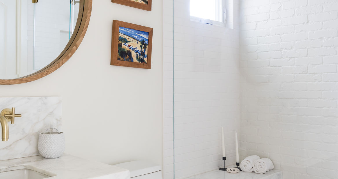 a bathroom with a circular mirror and a tile shower