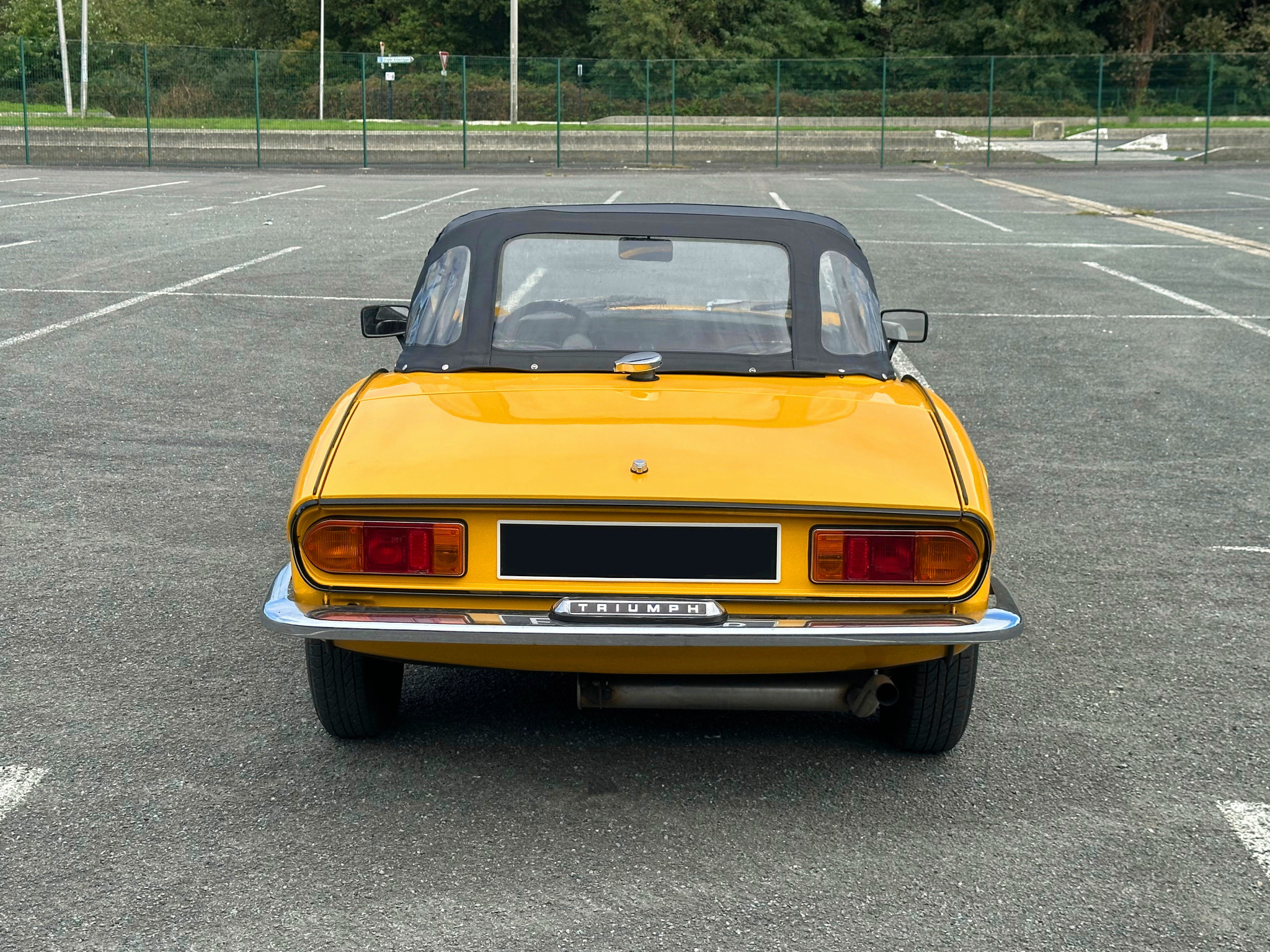 Vue arrière de la Triumph Spitfire jaune avec capote