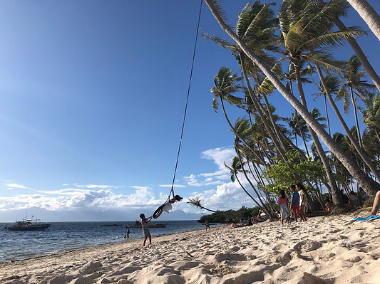palm trees and beachgoers on Paliton Beach in Siquijor, Philippines