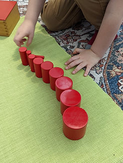 Image of a child lining up red cylinder blocks.