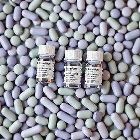 sage green and light purple pills with multiple small medicine bottles with different anti