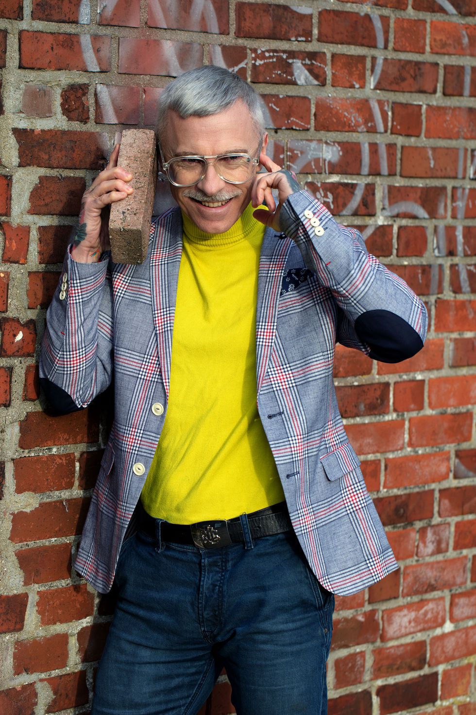 Christoph hält einen Backstein am Ohr.