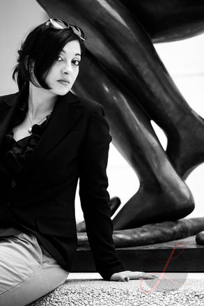 Frau in schwarzer Kleidung posiert an einem Kunstwerk in Paris.