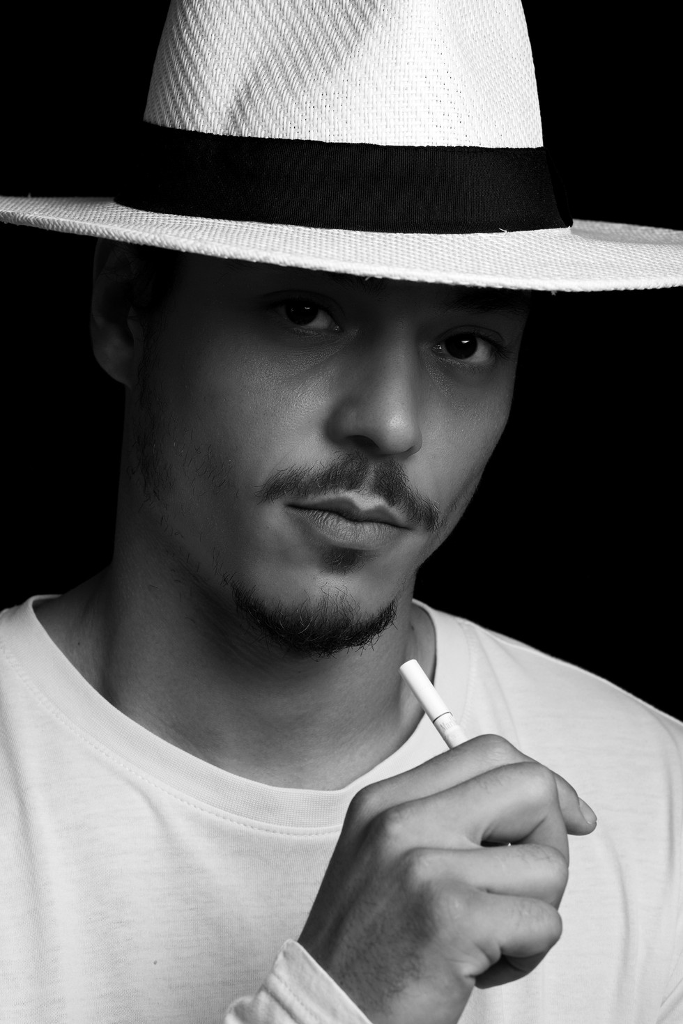 Amir mit weißem Sommerhut. Studioaufnahme. Schwarzweiß.