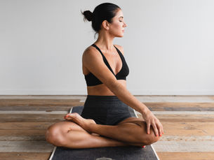 Eine Frau sitzt beim Yoga im Schneidersitz