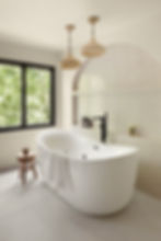 Serene bathroom with a freestanding tub, arched tile niche, black fixtures, and warm pendant lighting — The Peachy Home Co.