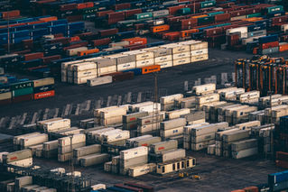 Stacks of shipping containers at a busy cargo port