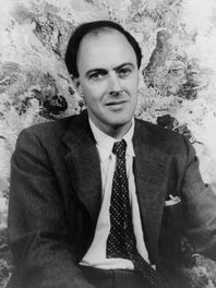 A black-and-white portrait of author Roald Dahl seated indoors.