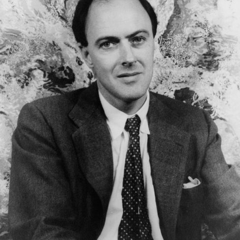 A black-and-white portrait of author Roald Dahl seated indoors.