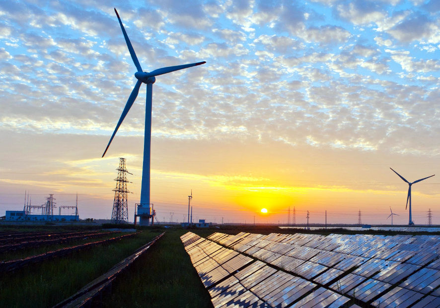 Solar panels, wind turbines and electricity pylons representing the energy transition