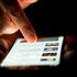 A person scrolling through news on a smartphone in low light