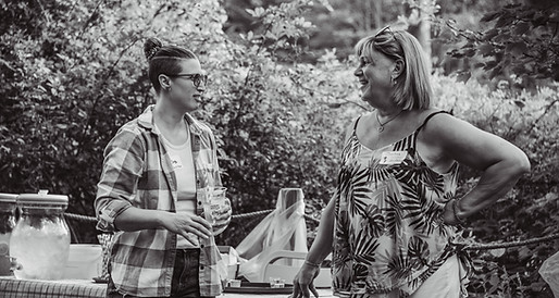 Two people smiling and talking in front of a table with refreshments.