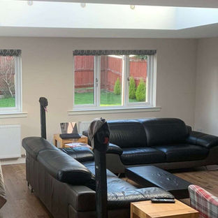 A large open-plan living and dining area with a covered table, leather sofas, and a skylight window