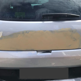 A grey car with a white dent at its back