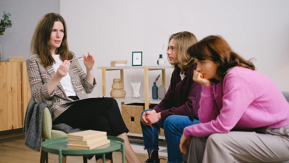 A counselor having a discussion with two students in an inviting, modern interior space.