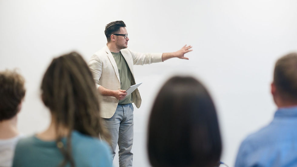 A man in a blazer gives a presentation to a captivated audience in a lecture setting.