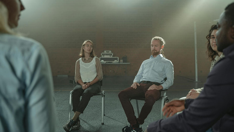 A diverse group of adults engaged in a thoughtful conversation indoors.